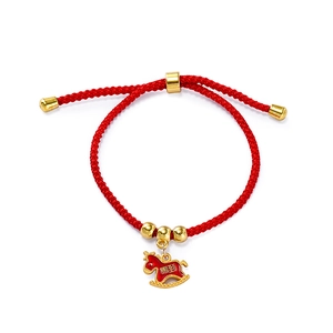 Detail of red braided New Year bracelet with golden rocking horse charm and beads