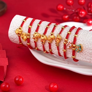 Detailed view of red woven bracelets with golden beads on a white cylinder stand