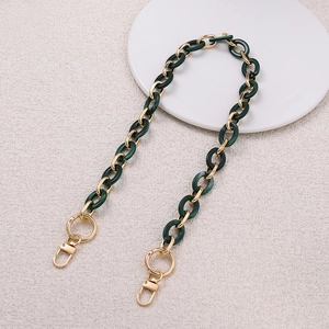 Close-up of dark green acrylic links and gold metal rings for DIY handbag straps