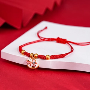 Macro detail of red woven bracelet with a white enamel rocking horse and gold beads