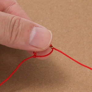 Makro-Detail der roten geflochtenen Kordel mit Goldfaden und verstellbarem Knoten für DIY