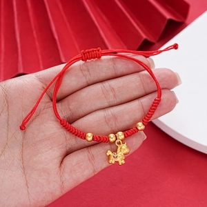 Detail of red woven bracelet with a gold horse charm and beads on a festive background
