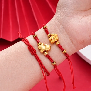 Detail of red woven bracelets with golden zodiac charms on a festive background