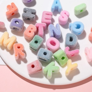 Close-up of colorful flocked acrylic letter beads for DIY jewelry making on white tray
