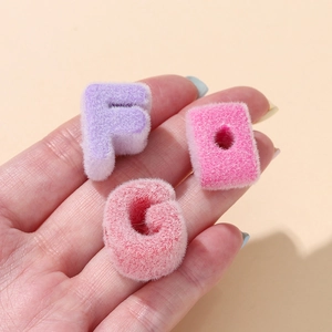Detailed close-up of soft flocked acrylic alphabet beads F, G, and O for DIY jewelry