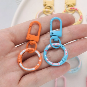 Hand holding orange and blue donut spring ring buckles with polka dots for DIY keychains