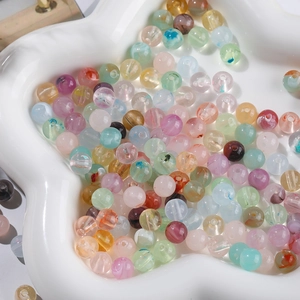 Macro shot of 8mm colorful marble-effect acrylic beads in a white floral dish for DIY