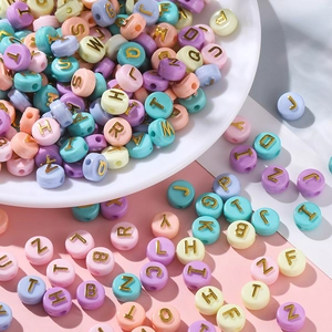 Macro detail of macaron acrylic beads with golden letter engraving for DIY jewelry making