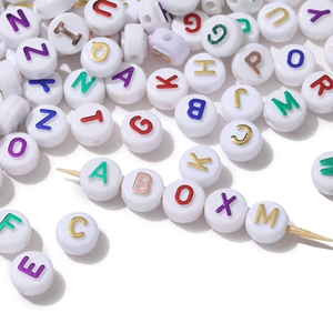 Macro detail of white acrylic letter beads with gold foil alphabet for DIY jewelry crafts
