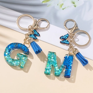 Portachiavi glitterato in resina con lettere G e M, farfalla blu e nappina decorativa