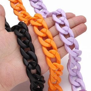 Acrylic handbag chain straps in black orange and purple shown held for size scale