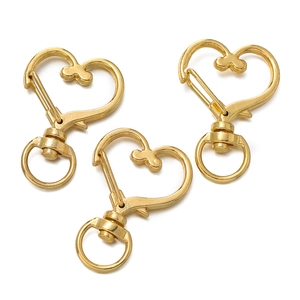 Close-up of three golden heart-shaped lobster clasps for DIY jewelry making and keychains