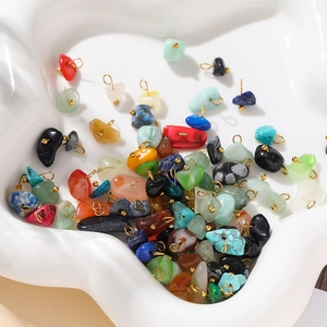 Macro shot of colorful natural stone pendants with gold loops on a white tray
