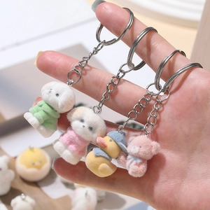 Detailed view of four flocked animal keychains featuring a bear, duck, and puppies on a hand