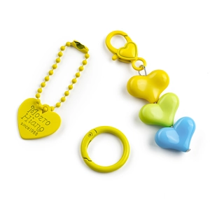 Detail of candy-colored heart beads and engraved yellow pendant on a lobster clasp