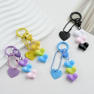 Close-up of heart-shaped beaded keychains in purple, yellow, blue, and black resin