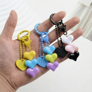 Colorful resin heart keychain set with metal bead chains held in hand against white background