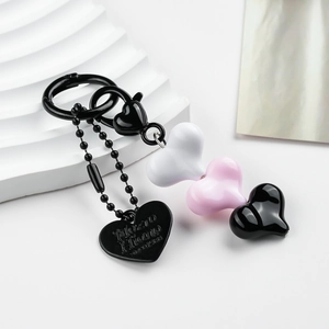 Close-up of heart-shaped resin beads and engraved metal tag on a stylish keychain