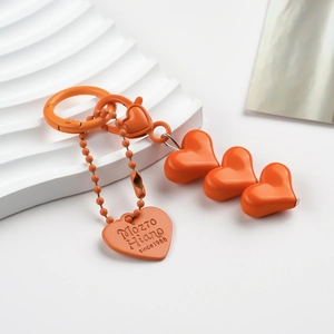 Detailed view of orange heart-shaped beaded keychain with polished metal clasp on white surface