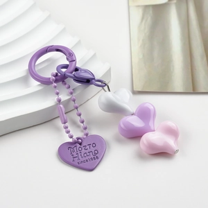 Detail of colorful resin heart charms and engraved metal tag on a sweet style keychain