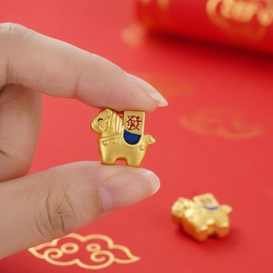 Detalle de un dije de caballo dorado con carácter chino de la suerte sobre la yema del dedo