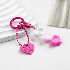 Macro view of magenta beaded heart keychain with engraved tag on a white background