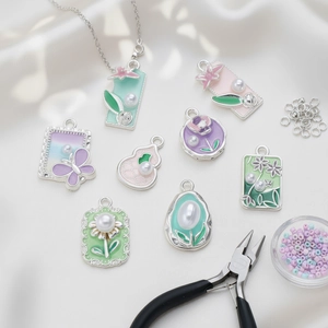 Macro detail of pastel enamel butterfly and flower pendants with faux pearls for DIY jewelry