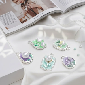 Flat lay of vintage silver pendants with colorful enamel flowers on white silk background