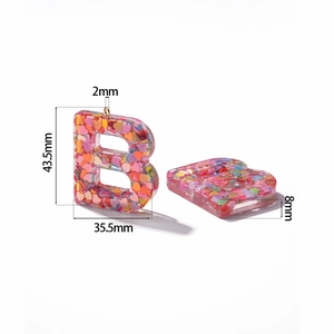 Macro shot of resin letter B pendant with pink sequins and dimensions 43.5x35.5mm