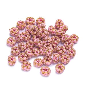 Detailed view of handmade pink and gold braided thread beads for DIY jewelry making