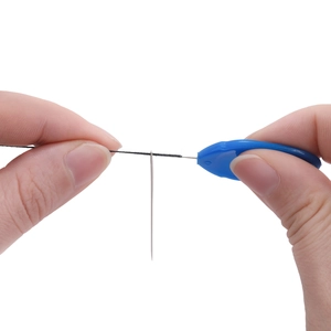 Macro shot of blue acrylic needle threader tool passing wire through a sewing needle eye