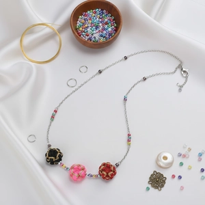 Close-up of handmade colorful woven flower beads with golden thread and silver chain link