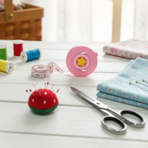 Detailed view of pink cartoon mini tape measure with sewing tools and fabric background