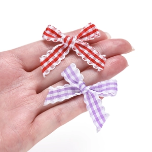 Red and purple plaid fabric bow accessories for DIY hair clips shown in hand