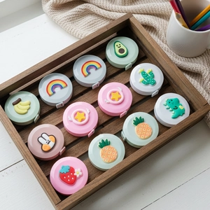 Close-up of cute cartoon portable mini tape measures with 3D silicone icons in a wooden tray