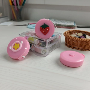 Pink strawberry mini measuring tape in a portable sewing kit with colorful thread