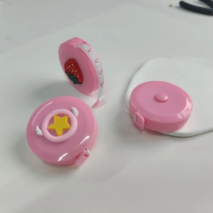 Detailed top view of three pink mini retractable tape measures with cute cartoon patterns