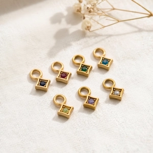 Detail of colorful cubic zirconia charms in gold plated stainless steel settings