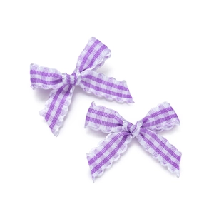 Macro detail of two purple gingham bow accessories with elegant wavy lace edges
