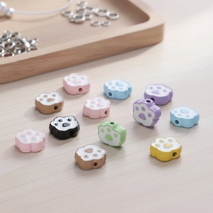 Colorful cat paw charms for DIY jewelry making on a natural wood background