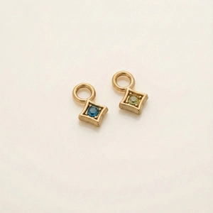 Close-up of gold-plated rhombus pendants with blue and green cubic zirconia gemstones