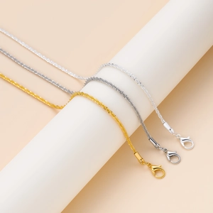 Detalle de tres collares DIY en oro, plata y negro con cierres de mosquetón