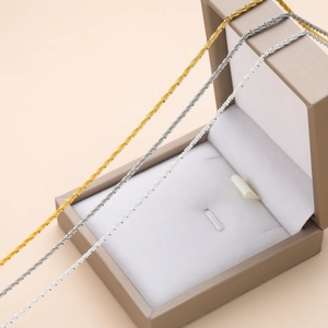Vista macro de cadenas tipo box doradas y plateadas en estuche de regalo de terciopelo