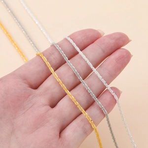 Primer plano detallado de tres colores de cadenas finas tejidas en espiral en una mano