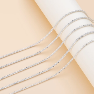 Primer plano detallado de collares de cadena popcorn plateada en soporte minimalista