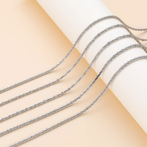 Detalle de cadena de plata para collar DIY en base blanca con iluminación suave