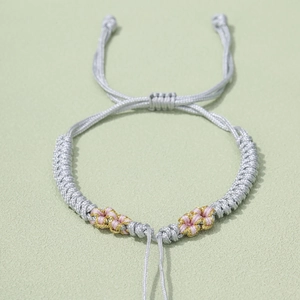 Detailed view of handmade peach blossom knot bracelet with adjustable silver-gray cord