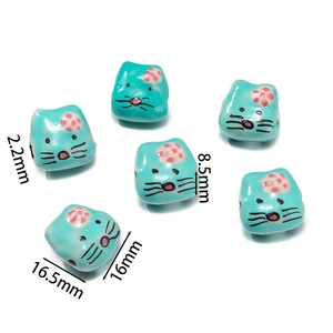 Macro detail of cat-shaped blue ceramic beads with hand-painted floral patterns and size marks