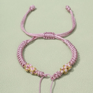 Detail of pink hand-woven bracelet with gold silk thread and adjustable sliding knot