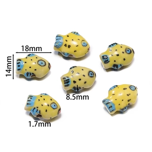 Macro shot of 18mm yellow handmade ceramic fish beads for jewelry with 1.7mm hole size